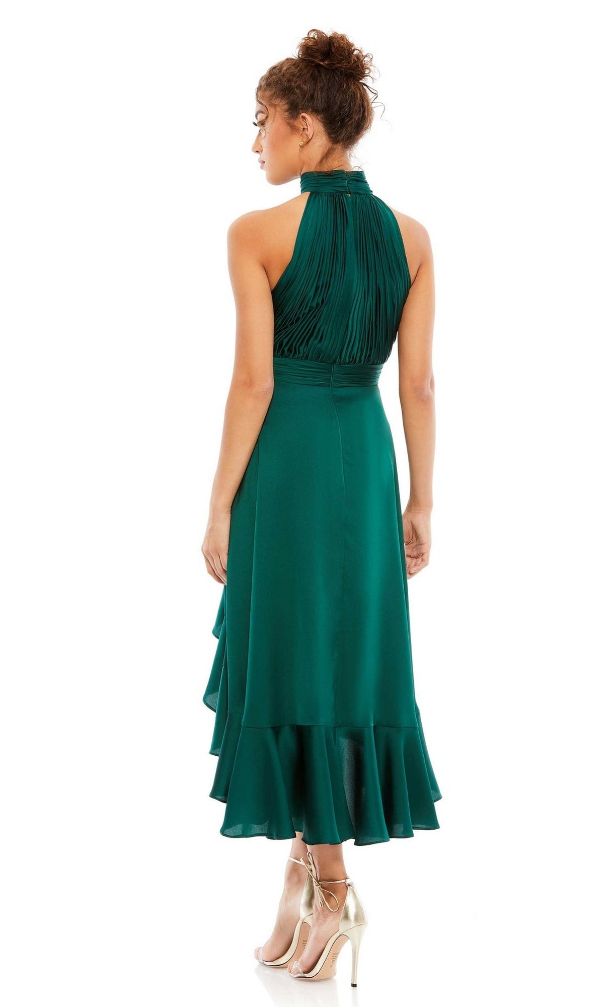 A woman in a sleeveless, emerald green Mac Duggal 49488 high-low wedding guest dress with a halter neck and ruffled hem is seen from the back, paired with gold high-heeled shoes.